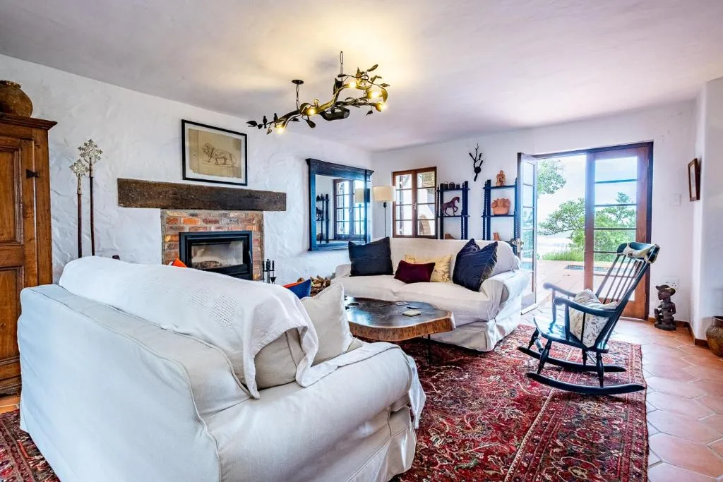 Spacious living room with white sofas, fireplace, and garden views