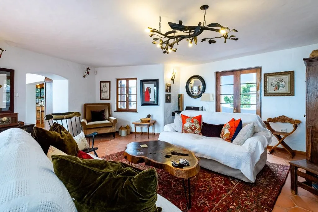 Spacious living room with white sofa, green velvet chairs, and artistic ceiling fixture