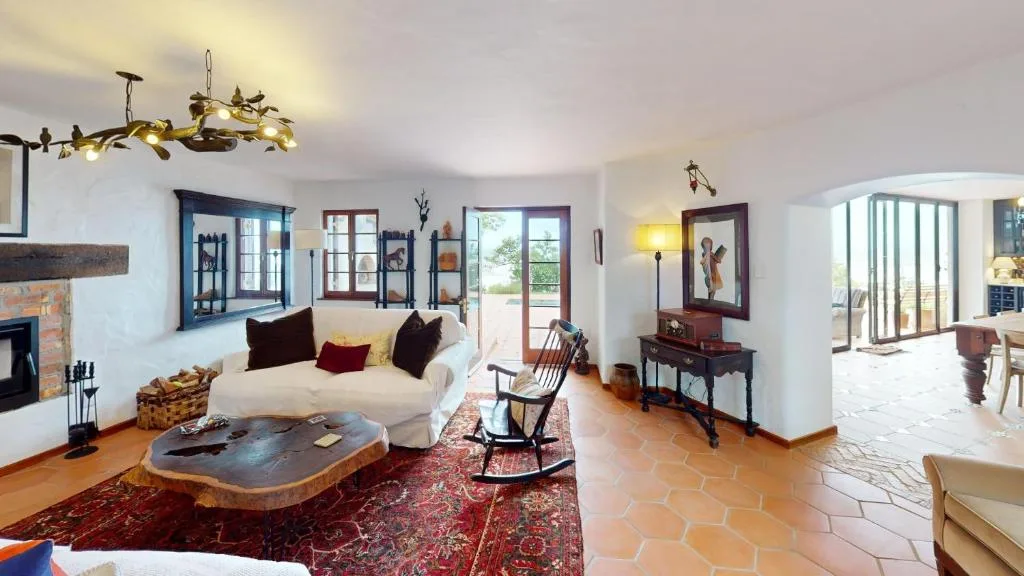Spacious living room with cream sofa, fireplace, and terracotta floors