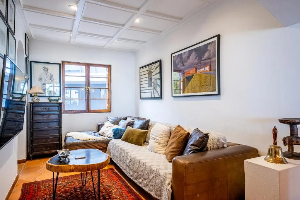 Bright lounge with brown leather sofa, colorful cushions, and framed artwork