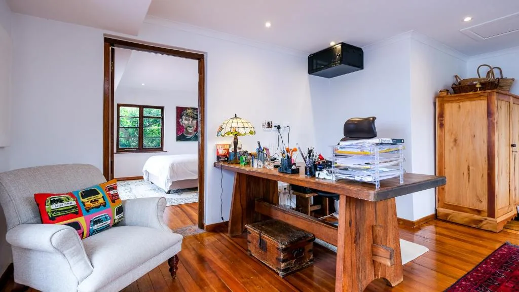 Bright lounge with cream armchair, wooden desk, and bedroom view
