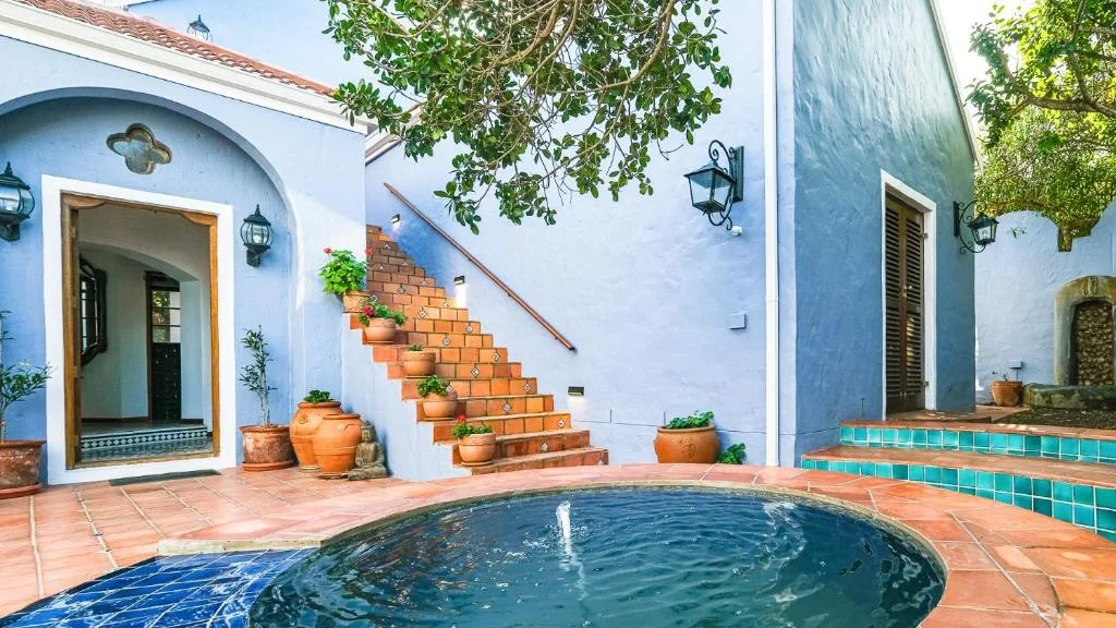 Round plunge pool in courtyard with blue-painted building and terracotta tiles