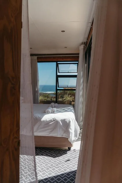 Bright bedroom with ocean view through large windows and white bedding
