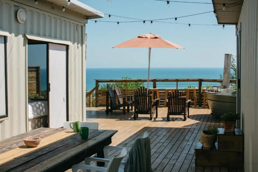 Spacious wooden deck with ocean view, umbrella, and dining furniture