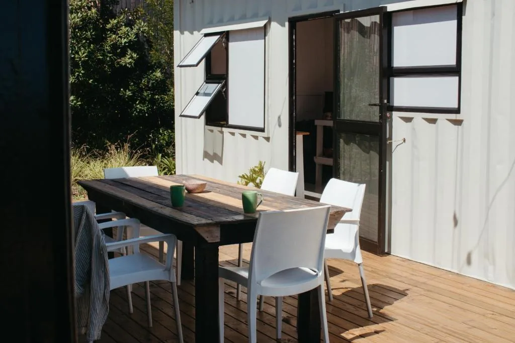 Wooden deck with dining table and white chairs overlooking garden
