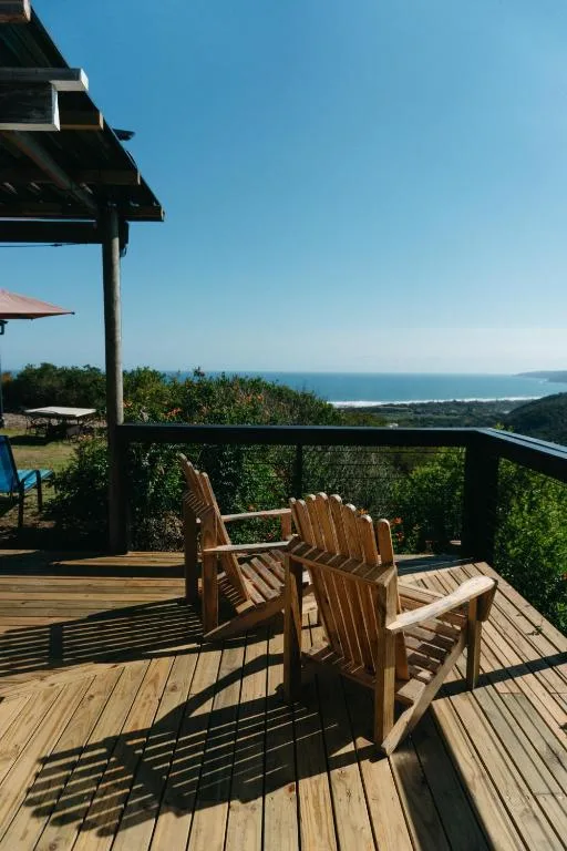 Wooden deck with Adirondack chairs overlooking ocean and coastline view