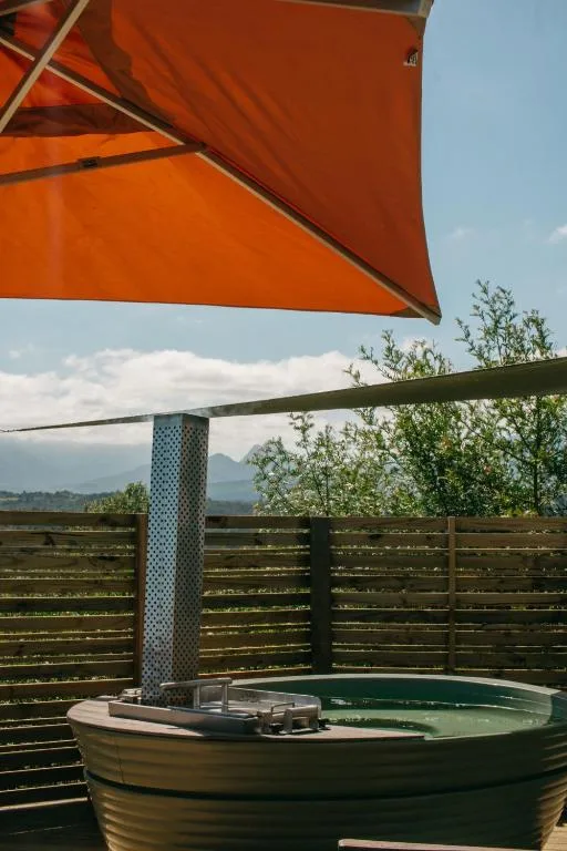 Outdoor hot tub under orange shade with mountain views beyond wooden railings