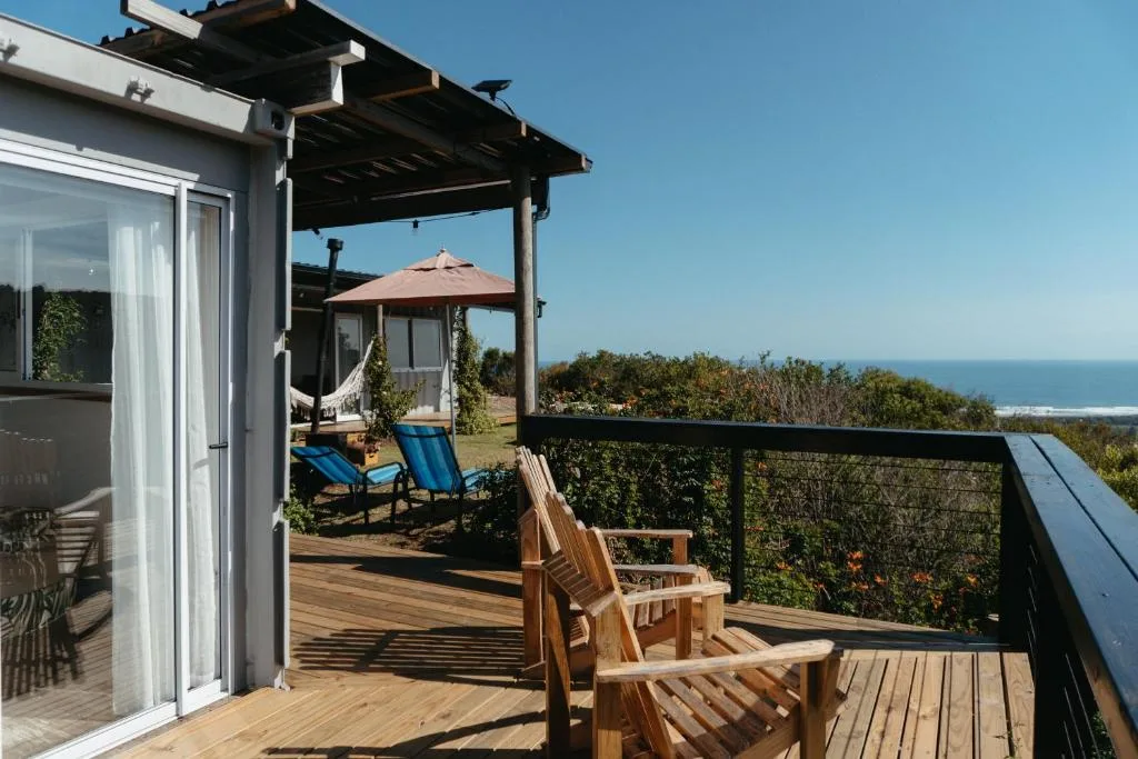 Wooden deck with ocean views, loungers, and pergola shade structure