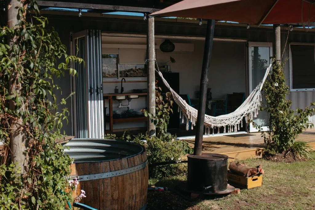 Covered outdoor deck with hammock, wooden barrel planter, and relaxation space