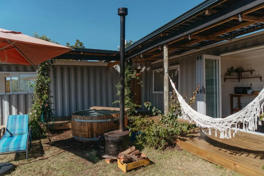 Outdoor deck with hammock, barrel hot tub, and red umbrella seating