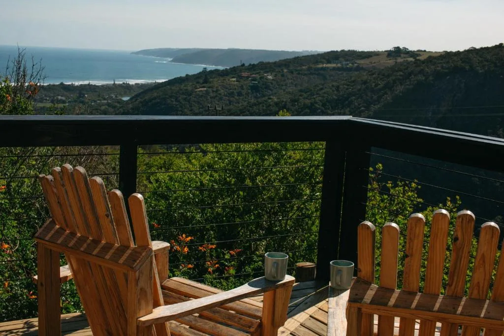 Wooden deck with Adirondack chairs overlooking coastal mountain landscape