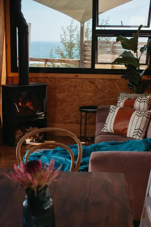Cozy lounge with fireplace, ocean views through large windows, comfortable seating