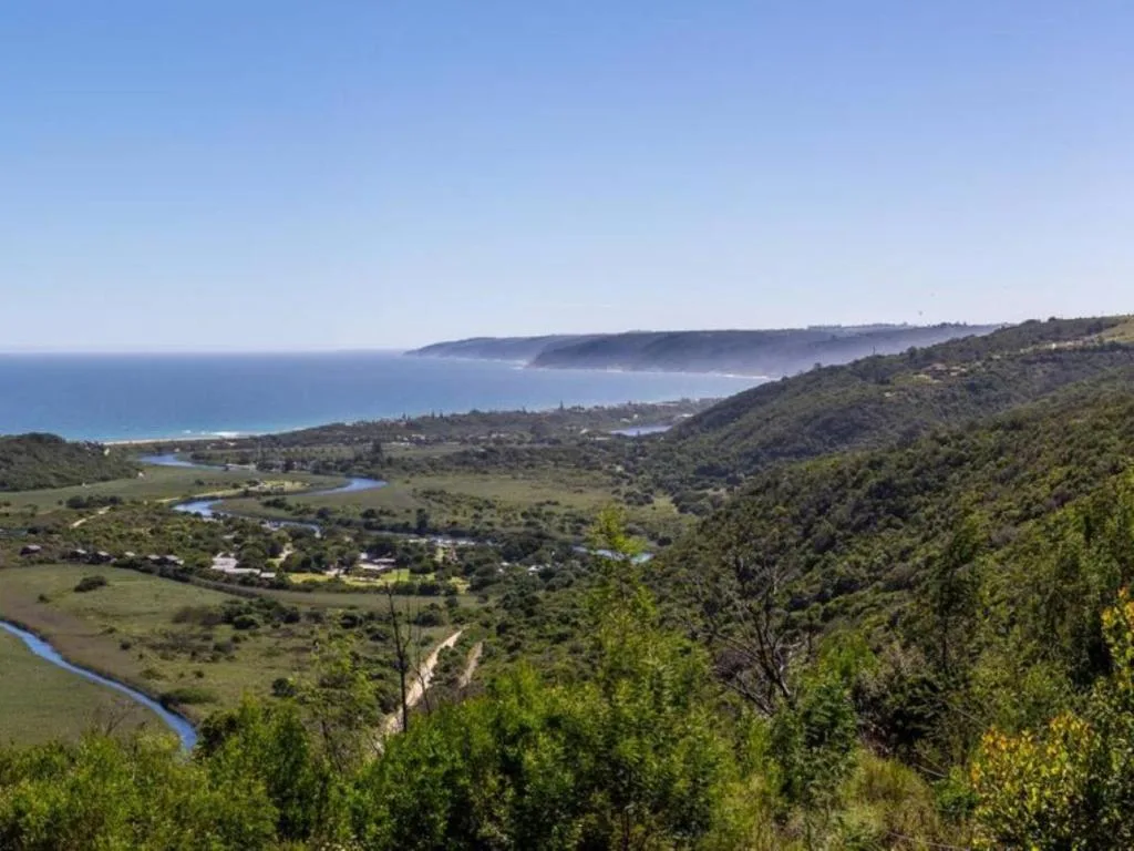 Sweeping coastal valley vista with ocean, lagoon, and forested hillsides