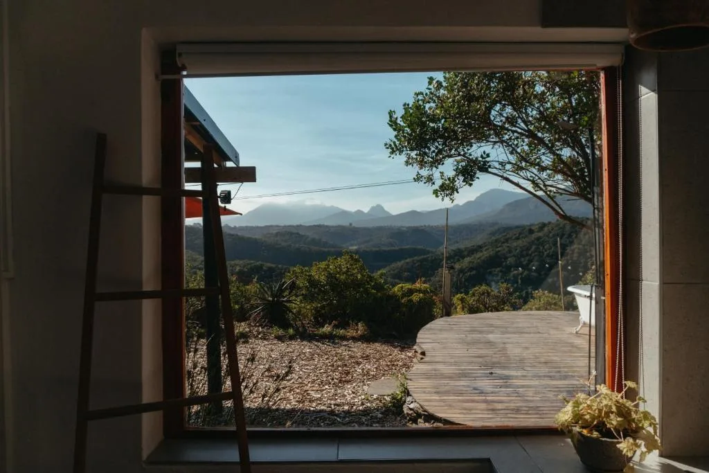 Mountain vista framed through open doorway with wooden deck and lush garden route landscape