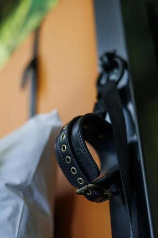 Close-up of black leather wristband with brass eyelets and buckle