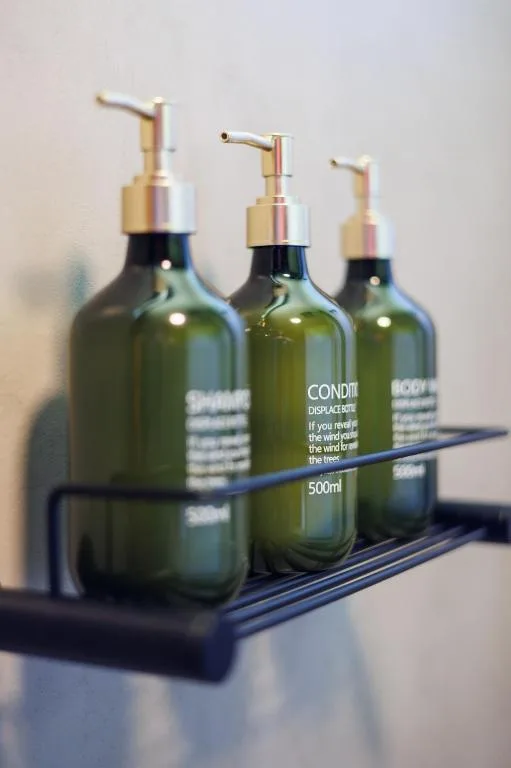 Three glass bottles of conditioner with gold pumps on black tray