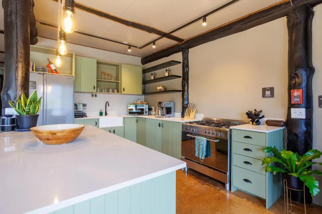 Modern kitchen with sage green cabinetry, stainless steel stove, and white countertop