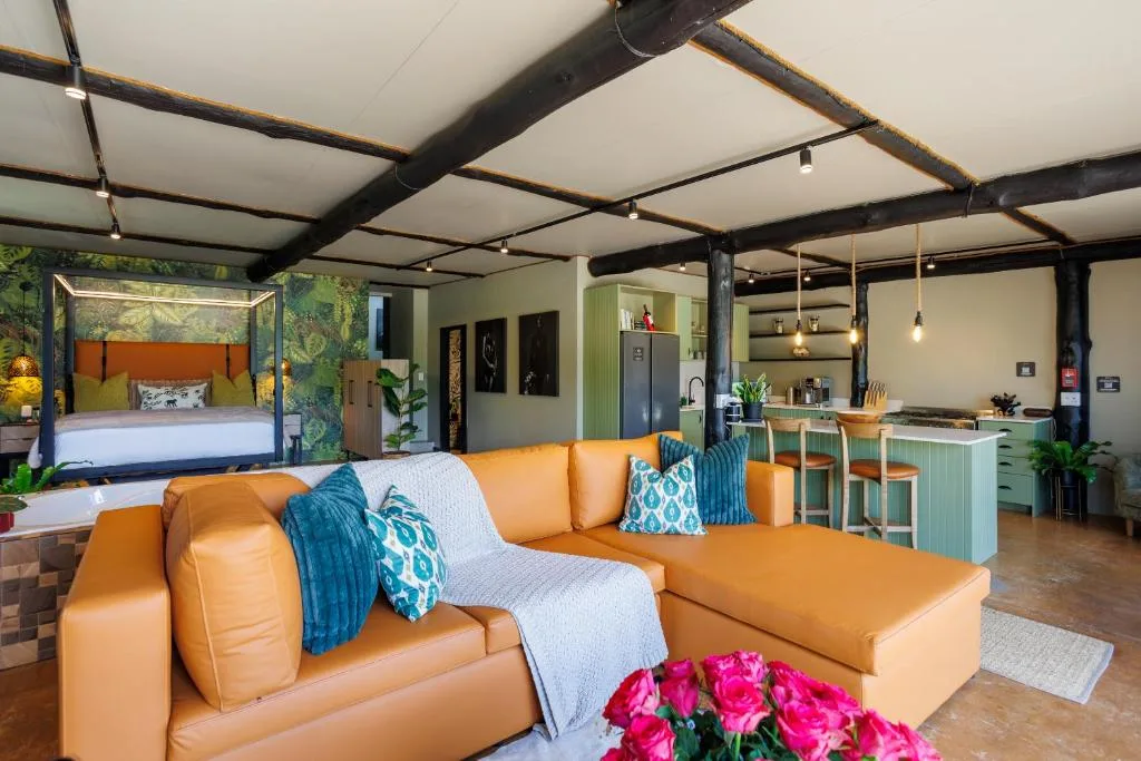 Modern lounge with orange leather sectional sofa, open-plan kitchen and bedroom visible