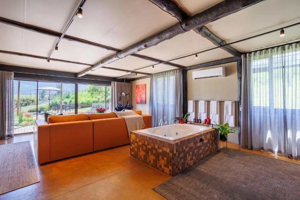 Modern lounge with orange sofa, wooden beams, and integrated hot tub