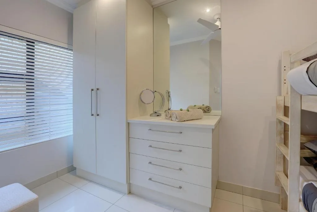 Modern white bathroom with vanity, mirror, and walk-in shower enclosure