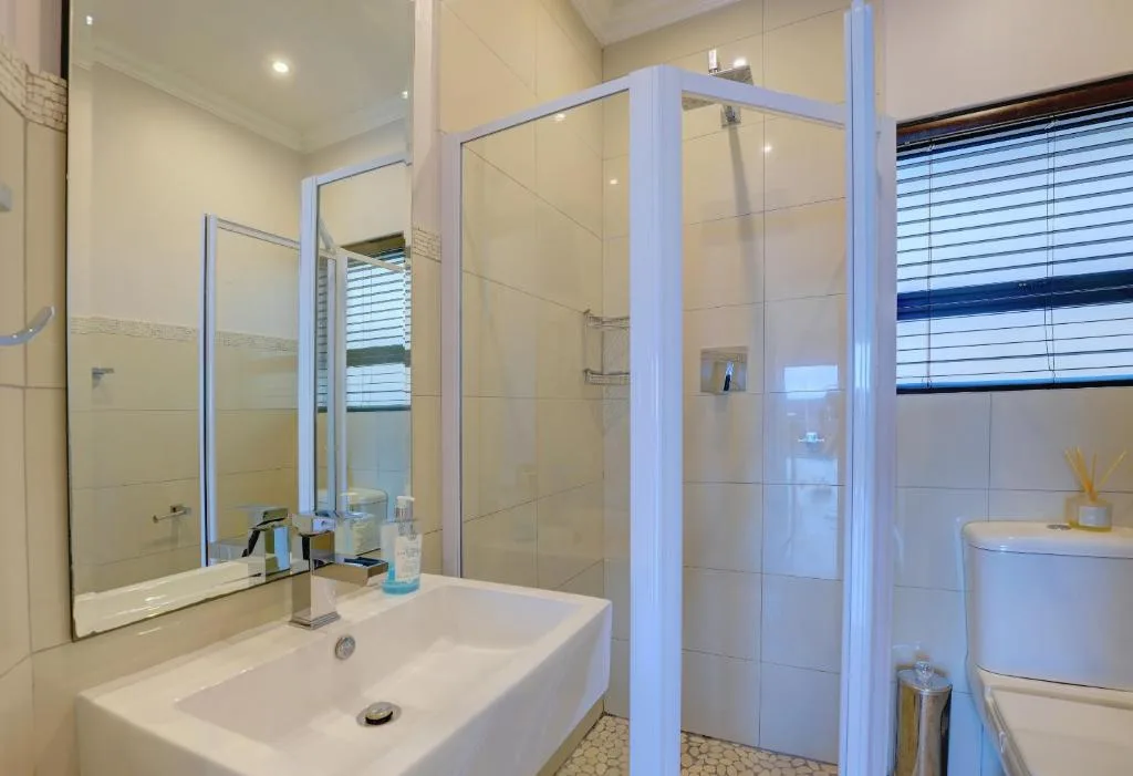 Modern bathroom with white vanity sink, mirror, and glass shower enclosure