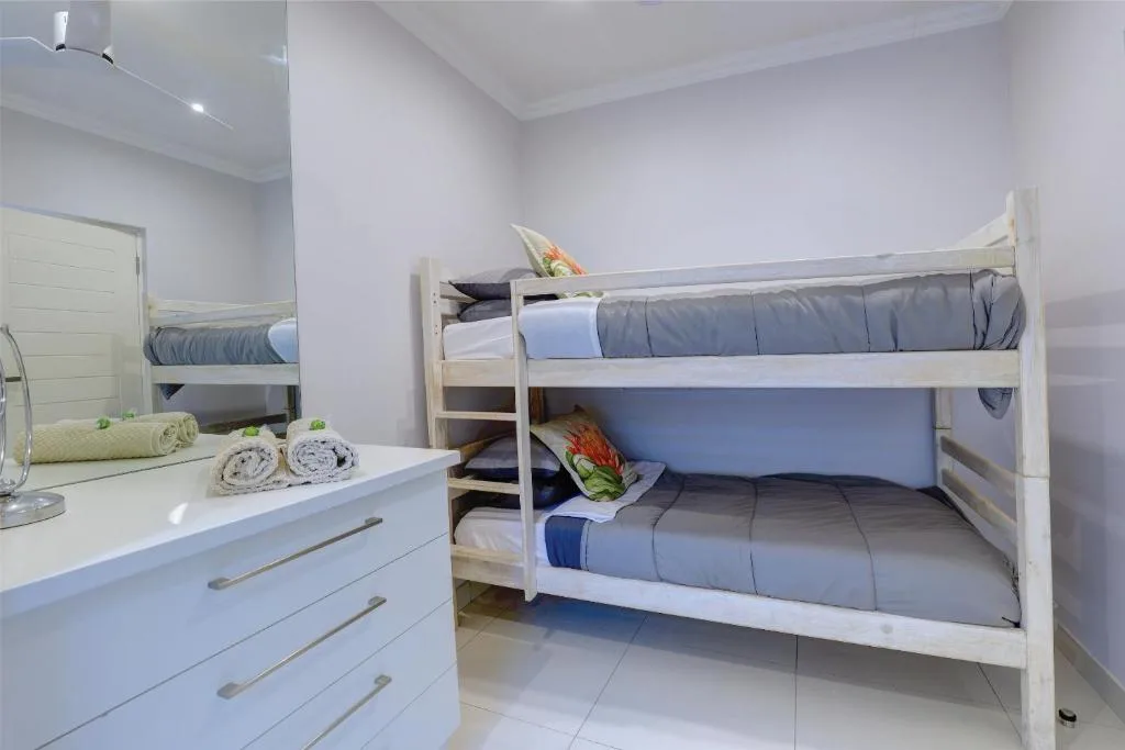 Bright bedroom with white bunk beds and folded towels on dresser