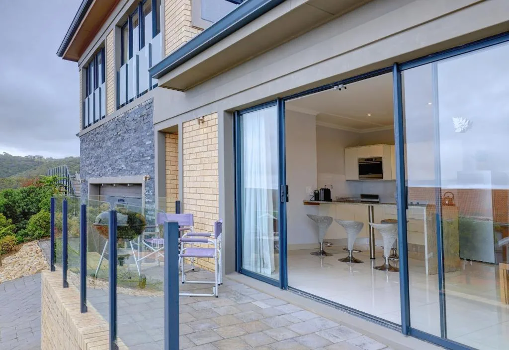 Paved patio with glass railing overlooking garden and mountains beyond