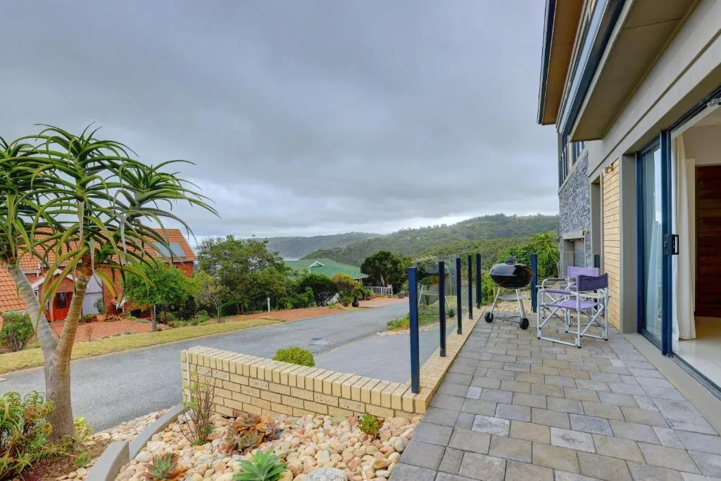 Paved patio with braai, seating, and garden views toward forested hills