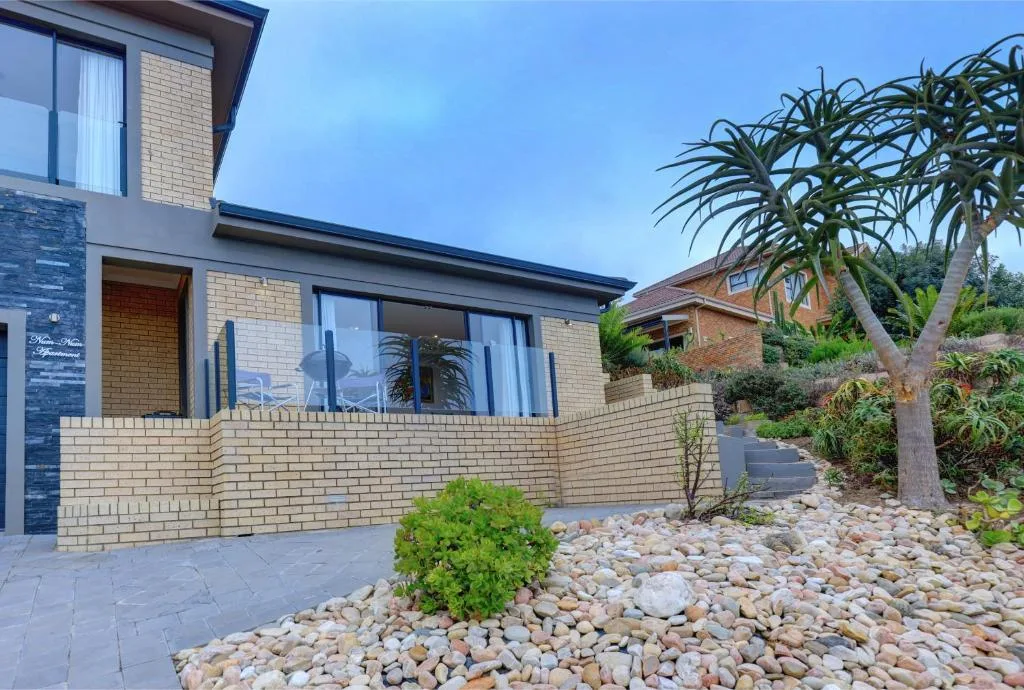 Modern brick cottage exterior with paved entrance and landscaped garden featuring palm tree