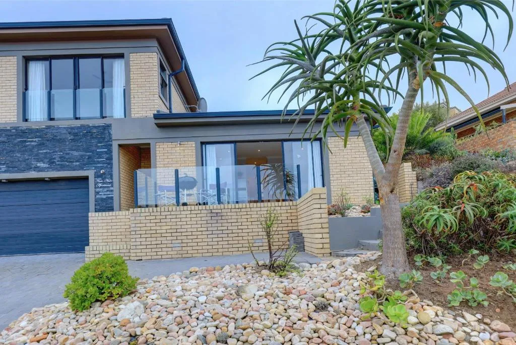 Modern brick home with large windows, palm trees, and landscaped stone garden