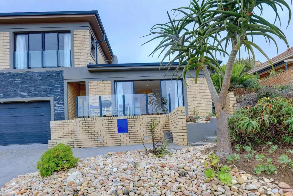 Modern brick home with large windows, palm tree, and gravel landscaping