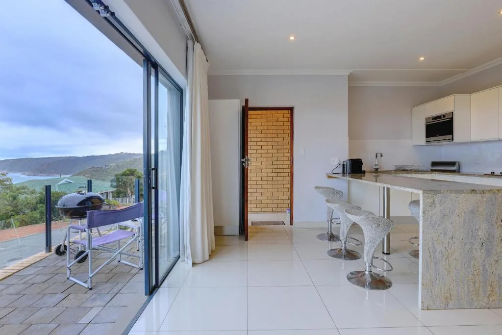 Modern kitchen with island seating and scenic coastal view through large windows