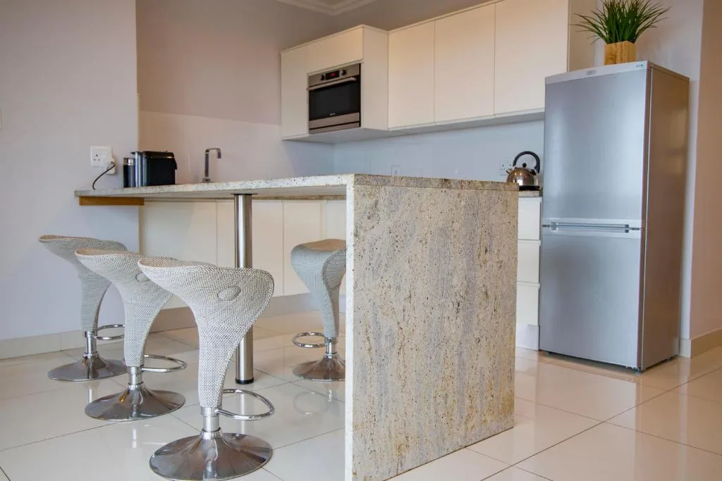 Modern kitchen with white cabinetry, granite island, and stainless steel appliances