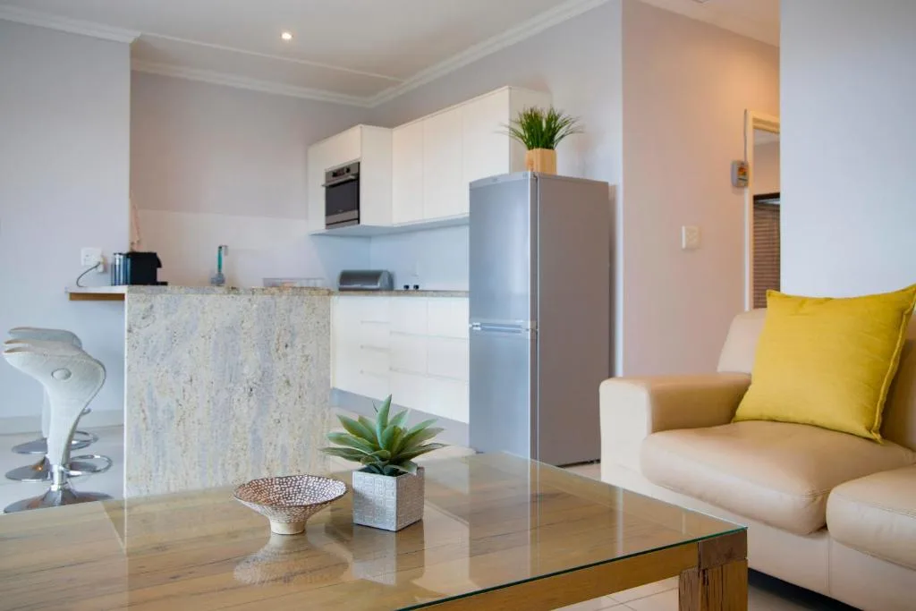 Open-plan lounge and kitchen with cream sofa and yellow cushion