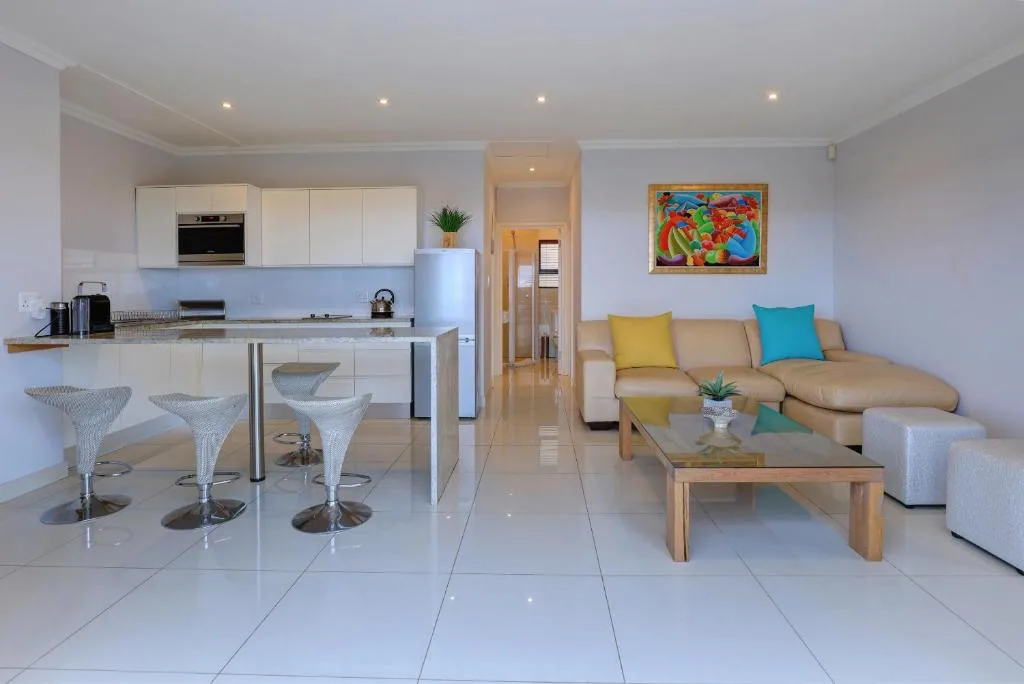 Open-plan lounge with beige sofa, colorful cushions, and modern coffee table