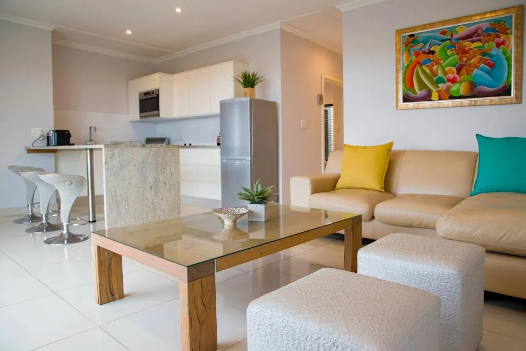 Open-plan lounge with tan sofa, colorful artwork, and modern furnishings