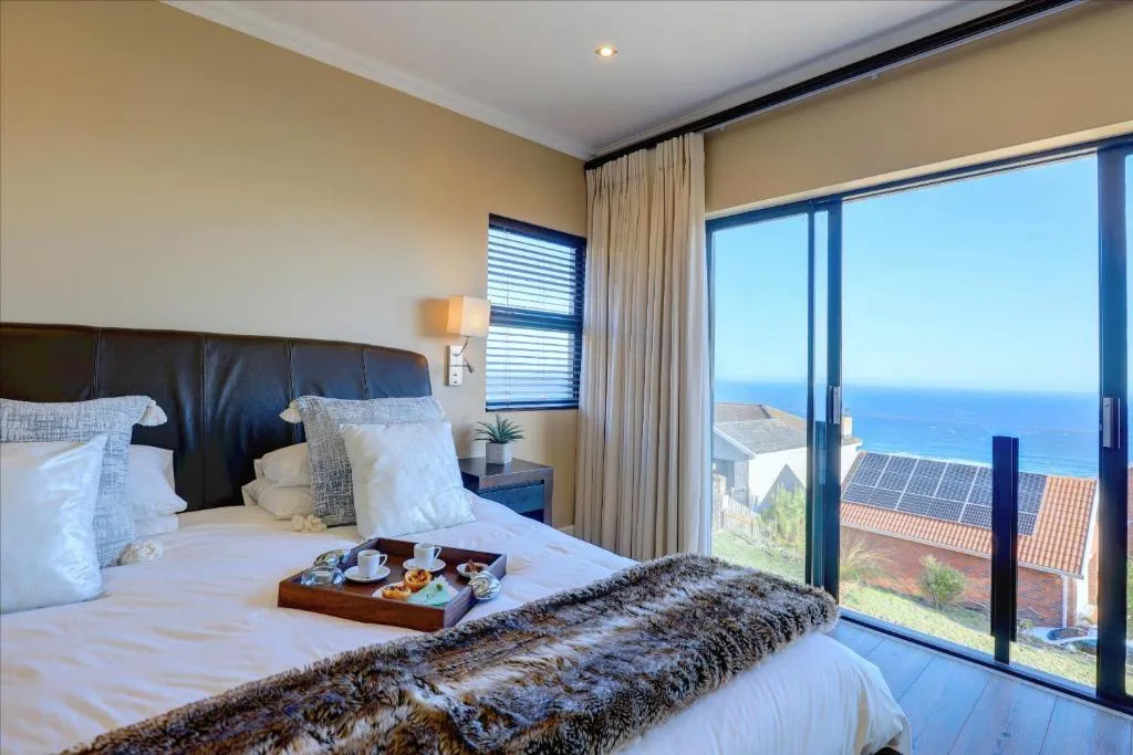 Luxurious bedroom with ocean view through sliding glass doors and coastal landscape
