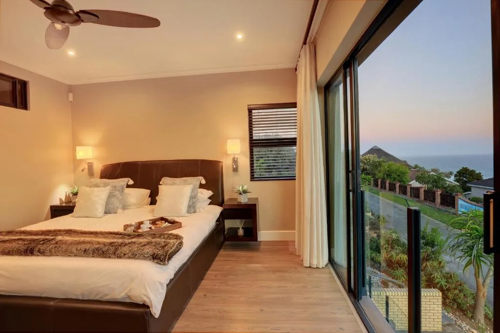 Spacious bedroom with ocean and mountain views through large windows