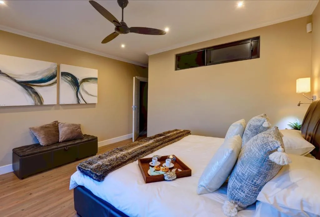 Spacious bedroom with queen bed, leather seating, and modern ceiling fan