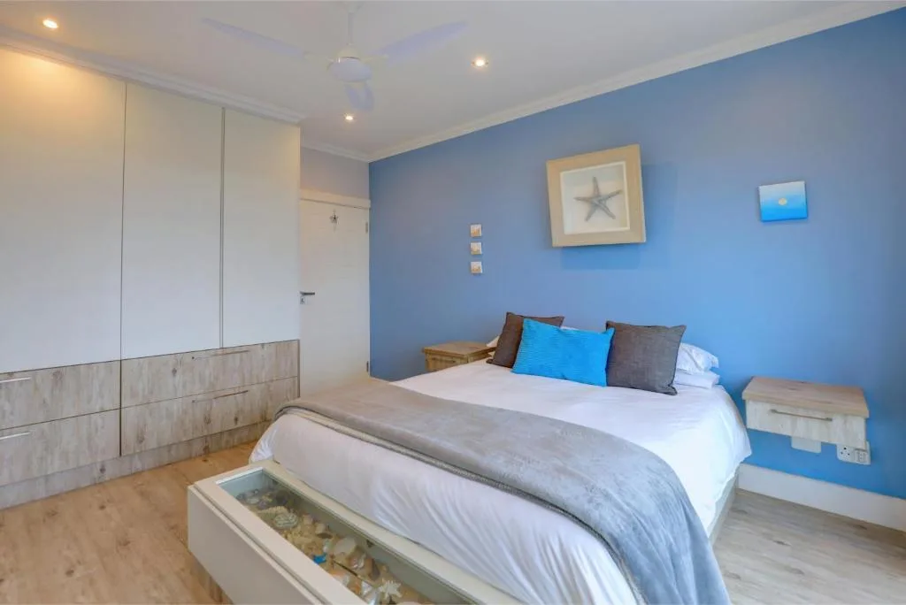 Bright bedroom with blue accent wall, double bed, and modern wooden furniture