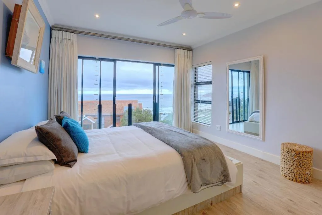 Spacious bedroom with ocean view through floor-to-ceiling windows and modern furnishings