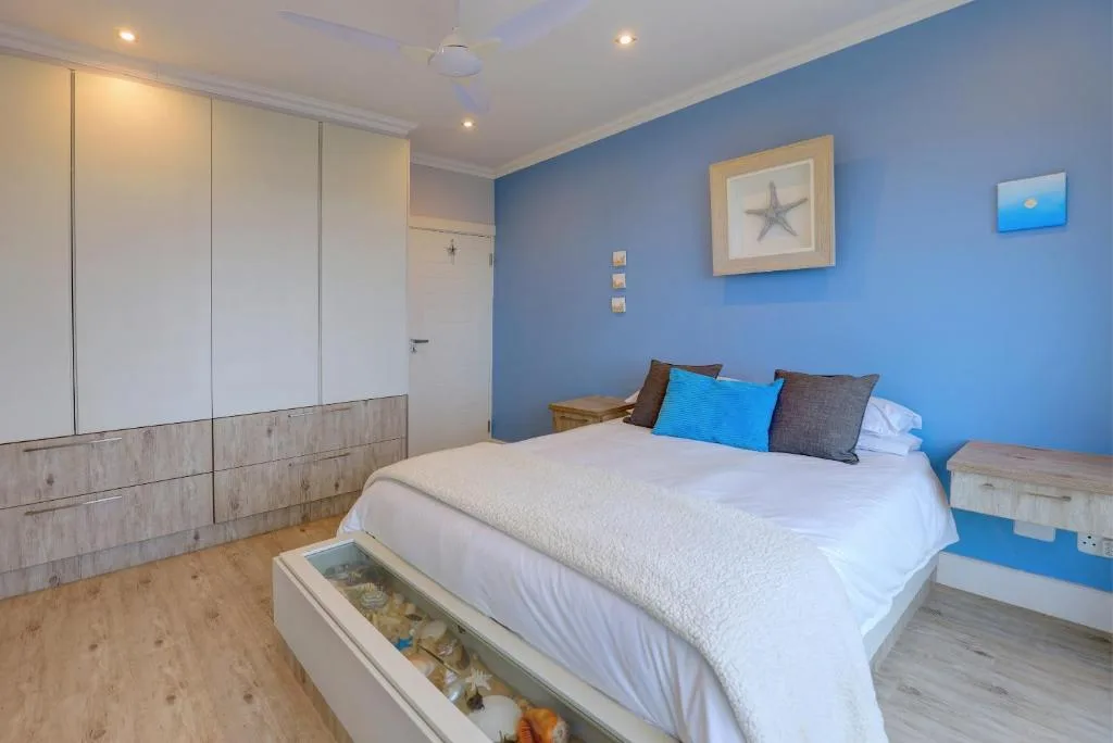 Bright blue bedroom with queen bed, built-in wardrobe, and coastal decor