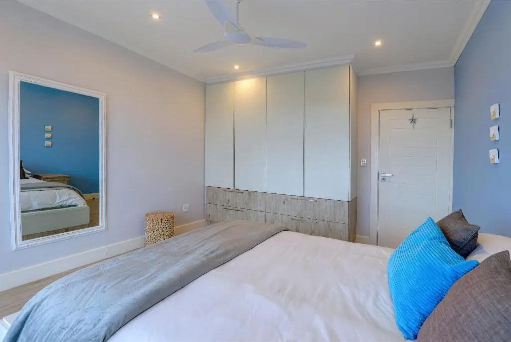 Modern bedroom with queen bed, blue accent wall, and built-in wardrobe storage