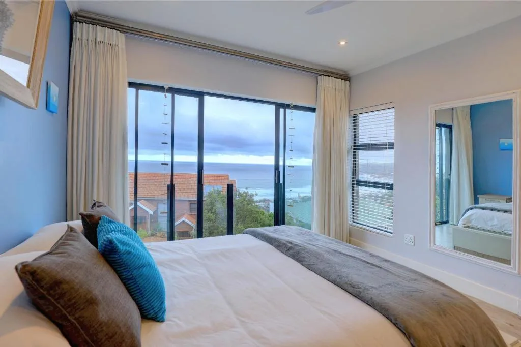 Spacious bedroom with ocean view through large glass doors and windows
