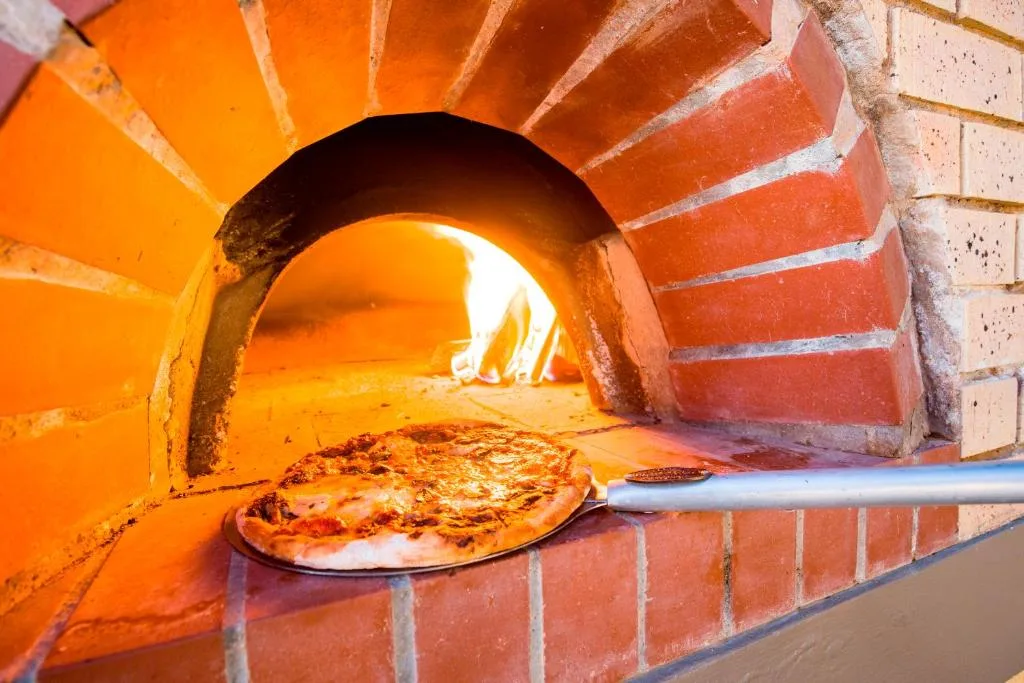 Traditional wood-fired pizza oven with freshly baked pizza inside