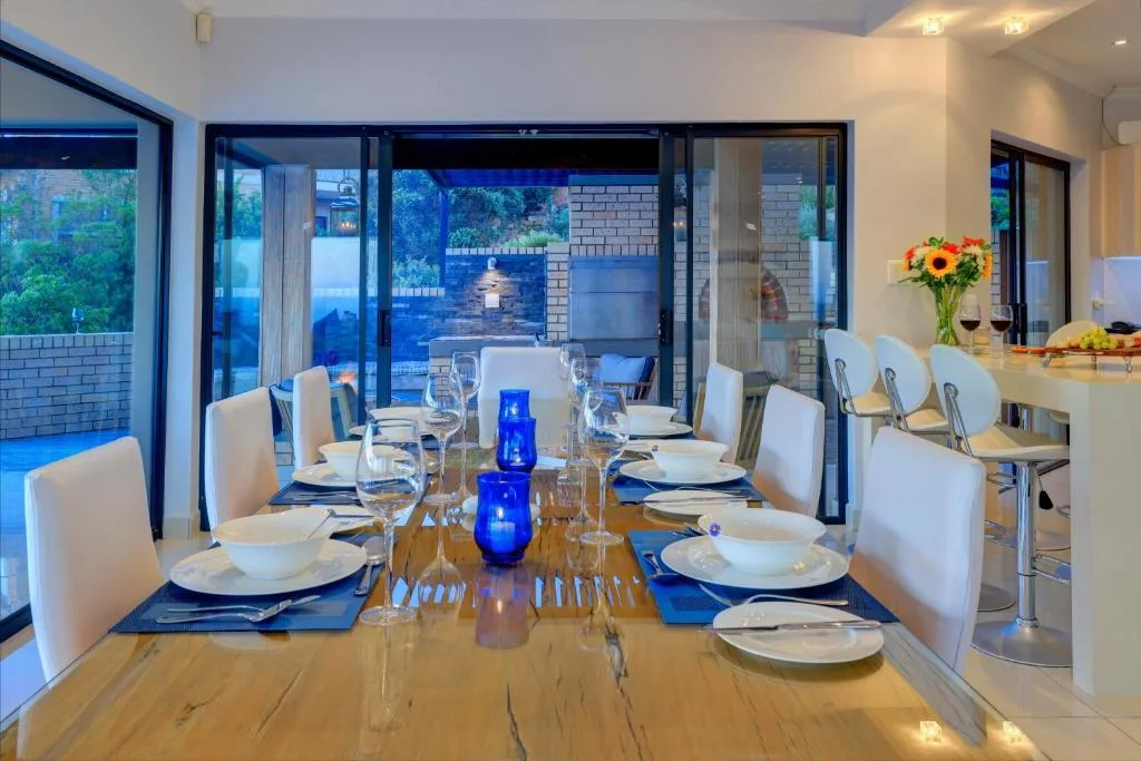Elegant dining table set for six with ocean views through floor-to-ceiling windows