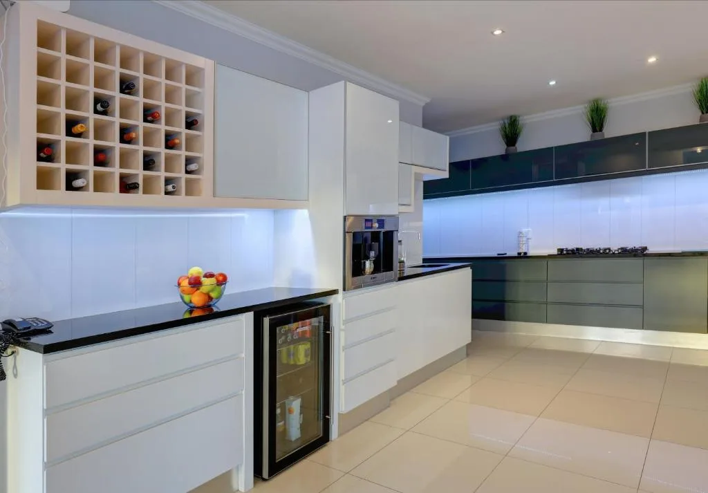 Modern kitchen with white cabinetry, black countertops, wine storage, and stainless appliances