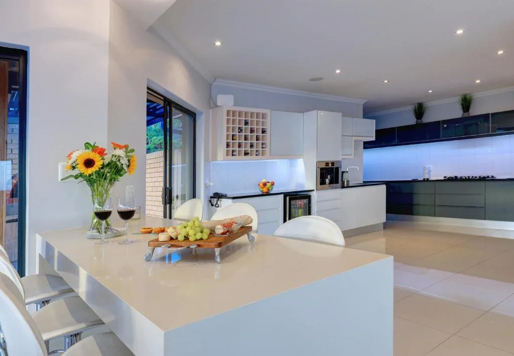 Modern open-plan kitchen with white cabinetry, island counter, and fresh flowers