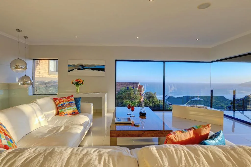 Modern lounge with sofa, pendant lights, and panoramic ocean view windows