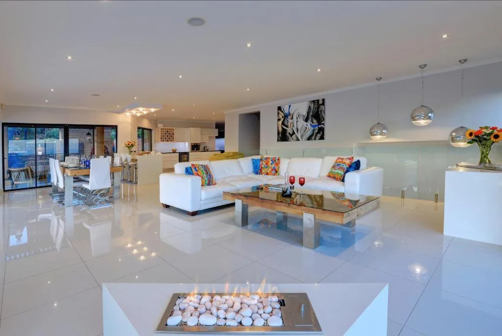 Modern open-plan lounge with white sofa, colorful cushions, and fireplace feature